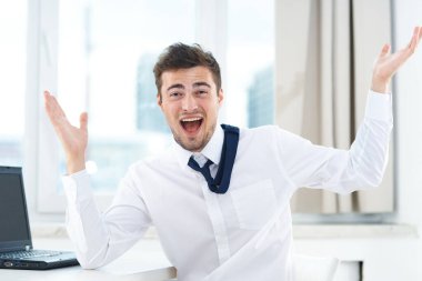 Ofiste dizüstü bilgisayarı olan mutlu genç bir iş adamı.