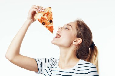 Güzel bir kadın arka planda pizza yiyor. 