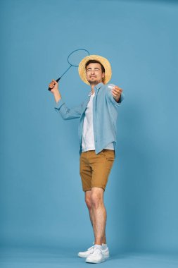 Tenis oynayan genç adam mavi arka planda izole edilmiş, stüdyo çekimi