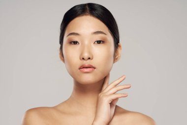 Stüdyo çekimi. Genç Asyalı kadın gride izole edilmiş.