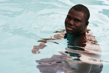 Havuzda poz veren genç yakışıklı adam.