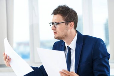 Genç yakışıklı işadamı belgeleri okuyor.