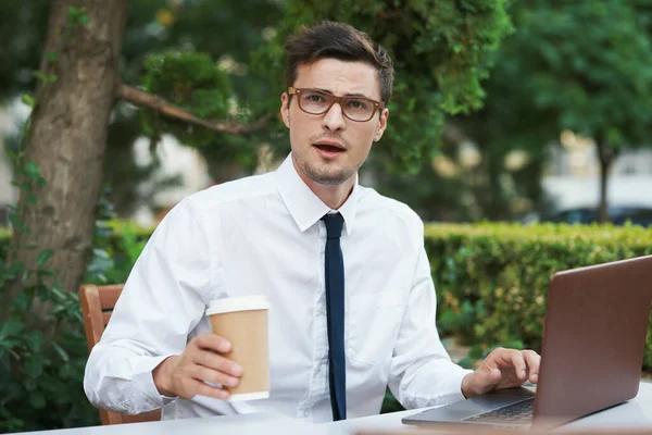 Young handsome  businessman with coffee cup and laptop