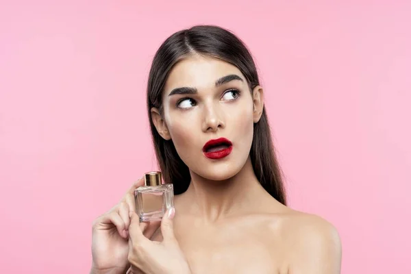Portrait of young beautiful  woman with perfume bottle. Studio shot