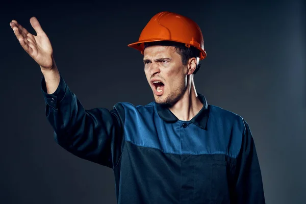 young angry man in work wear and helmet. Studio shot