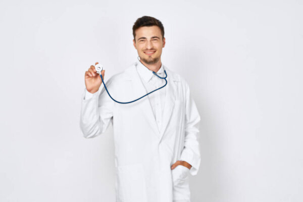 Studio shot. Young doctor holsing stethoscope on  isolated background 