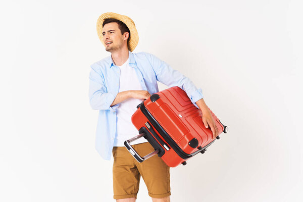 Young man with red suitcase in studio
