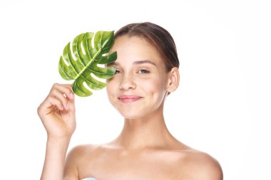 Stüdyoda yaprağıyla poz veren genç ve güzel bir kadın.