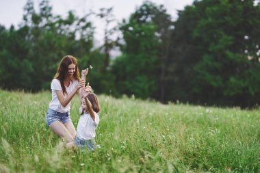 Genç anne ve kızı papatya tarlasında eğleniyorlar.