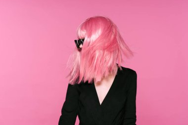 Pembe peruklu ve güneş gözlüklü genç bir kadın stüdyoda poz veriyor. 