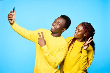 Genç ve güzel bir çift stüdyoda mavi arka planda selfie çekiyor.
