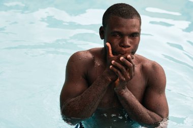 Havuzda poz veren genç yakışıklı adam.