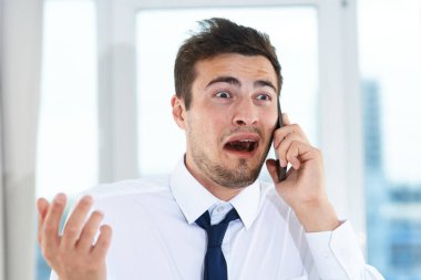 İş konsepti. Yong, iş adamının ofiste akıllı telefondan konuşmasına şaşırdı. 