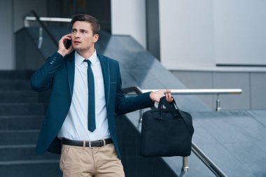 Genç yakışıklı işadamı akıllı telefondan konuşuyor. 