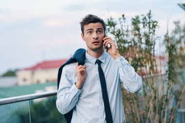 Genç yakışıklı işadamı sokakta akıllı telefondan konuşuyor. 
