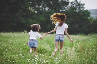 Genç anne ve kızı papatya tarlasında eğleniyorlar.