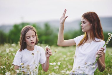 Genç anne ve kızı papatya tarlasında eğleniyorlar.