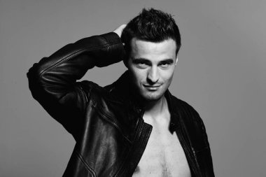 Stüdyoda poz veren deri ceketli yakışıklı bir genç. Siyah ve beyaz 