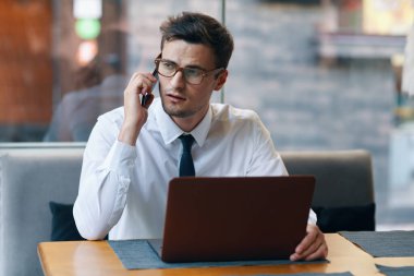 Bilgisayarı ve akıllı telefonu olan genç bir iş adamı. 