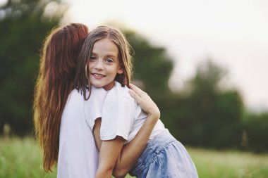 Genç anne ve kızı papatya tarlasında eğleniyorlar.