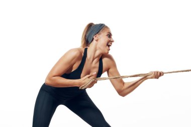 Stüdyo çekimi. Beyaz arka planda izole edilmiş halatla genç ve formda kadın eğitimi   