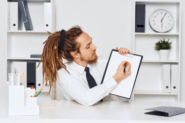 Ofiste oturan genç işadamı belgeleri gösteriyor.