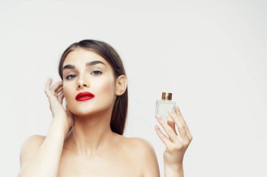 Beyaz arka planda parfüm şişesi olan güzel bir kadının portresi.