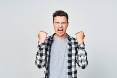 Stüdyoda yumrukları olan öfkeli genç bir adam, beyaz arka planda soyutlanmış.