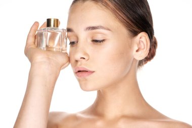 Beyaz arka planda parfüm şişesi olan güzel bir kadının portresi.