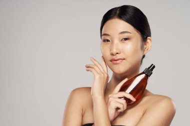 Stüdyoda saç spreyi kullanan Asyalı genç bir kadın. Güzellik, moda fotoğrafçılığı