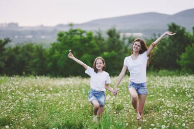 Genç anne ve kızı papatya tarlasında eğleniyorlar.