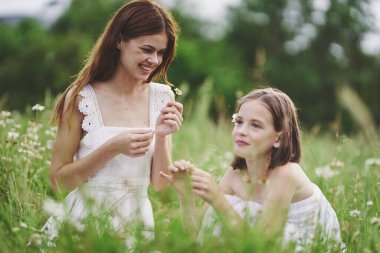 Genç anne ve kızı papatya tarlasında eğleniyorlar.