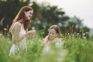 Genç anne ve kızı papatya tarlasında eğleniyorlar.