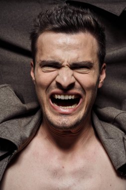 Genç yakışıklı duygusal adam stüdyoda poz veriyor.