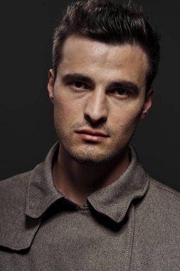 Stüdyo çekimi. Poz veren genç yakışıklı adamın portresi.