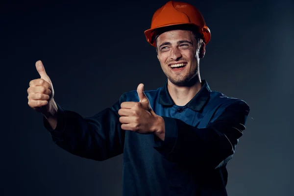 young man in work wear and helmet with thumbs up. Studio shot