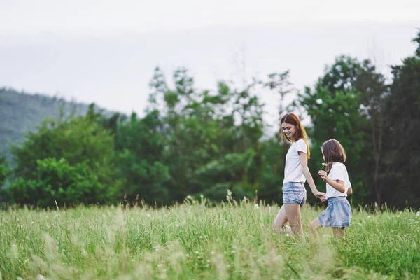 stock image Young mother and her daughter having fun on camomile field