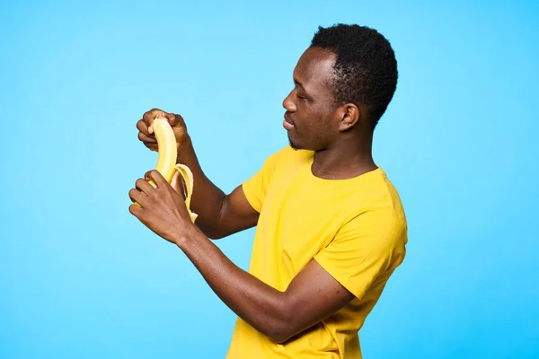 Young african man   with banana  isolated on blue background