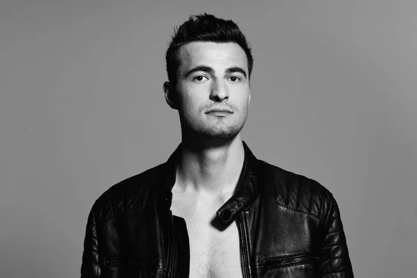 Young handsome man in leather jacket posing in studio. Black and white