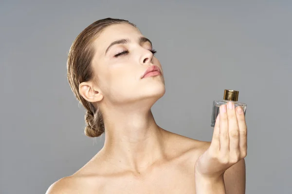 portrait of young beautiful woman with perfume bottle.  Studio shot.