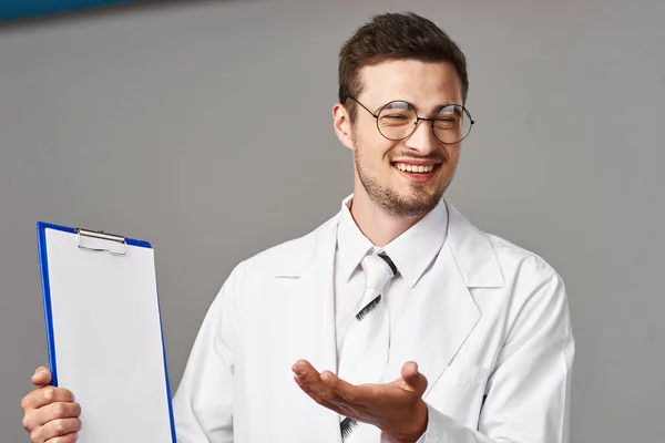 Tiro Estúdio Jovem Médico Mostrando Algo Isolado Fundo Cinza — Fotografia de Stock