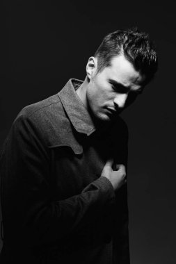 Siyah ve beyaz. Siyah arka planda gri ceketli genç adamın portresi. Stüdyo çekimi. 