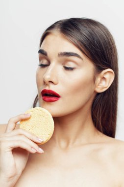 Genç ve güzel bir kadın yüzünü süngerle temizliyor. Güzellik rutini. Stüdyo çekimi