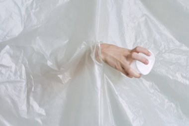Plastik ve polietilen yırtıklar olan bir kadın eli.