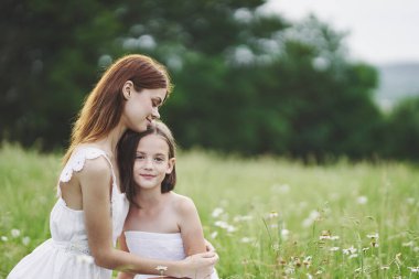 Genç anne ve kızı papatya tarlasında eğleniyorlar.