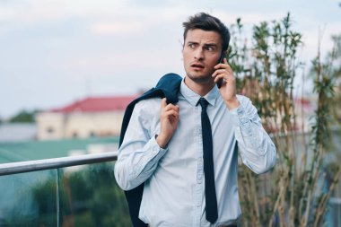Genç yakışıklı işadamı sokakta akıllı telefondan konuşuyor. 