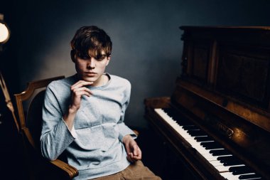 Genç piyanist piyano klavyesinin yanında oturuyor.