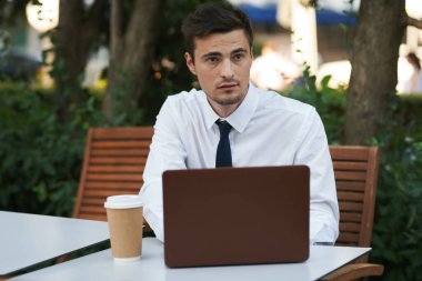 Kahve ve dizüstü bilgisayarlı genç bir işadamı.