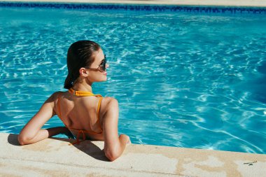 Genç ve güzel bir kadın havuzda dinleniyor.  