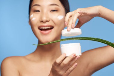 Genç güzel Asyalı kadın aloe vera yaprağıyla poz veriyor. 